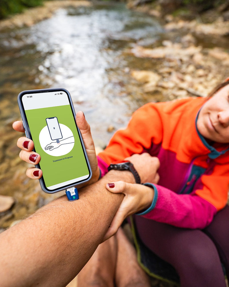 Person holding a phone with a heat it® outdoors by a stream